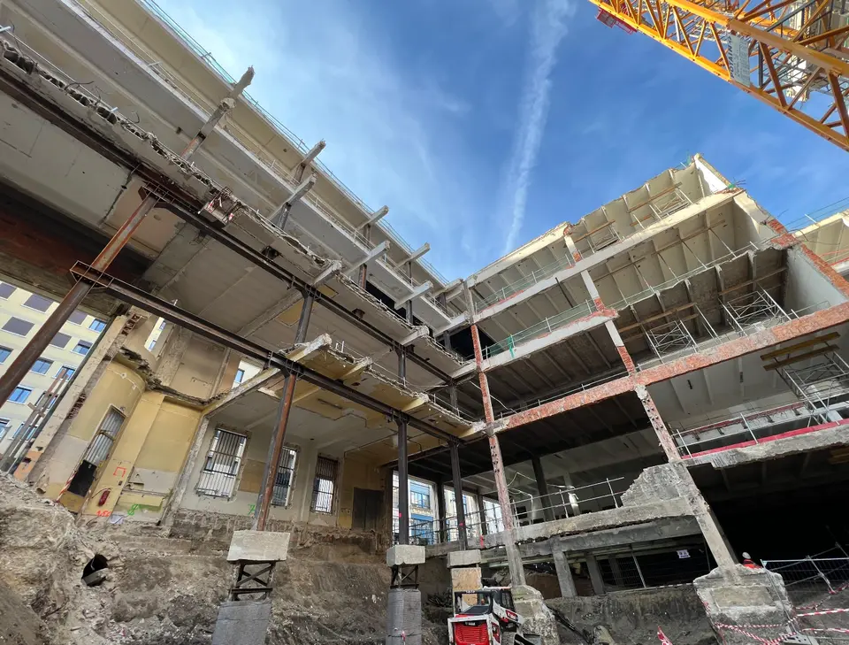 Vue d'ensemble du chantier : les planchers conservés reposent sur les files de profilés métalliques provisoires, au-dessus de la fouille.