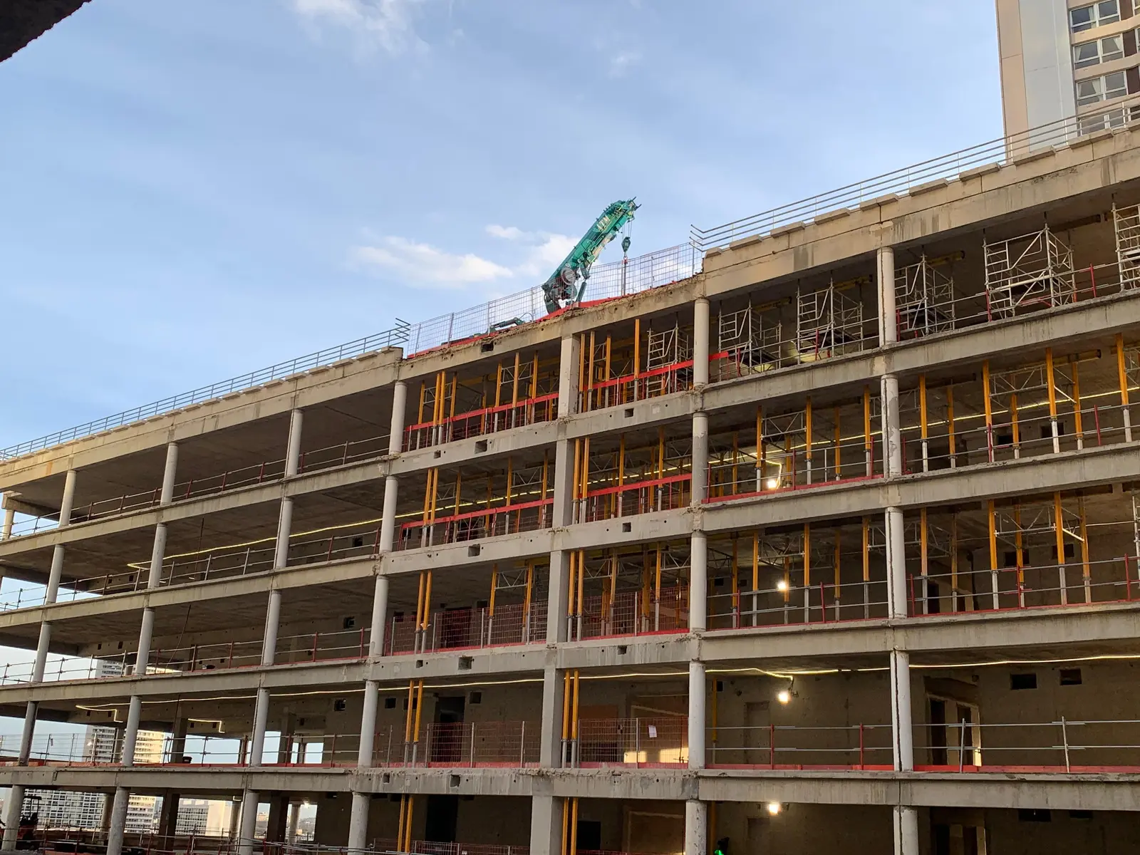 Vue d'ensemble de la façade du bâtiment PB10 pendant les travaux, avec la tour voisine en arrière-plan.