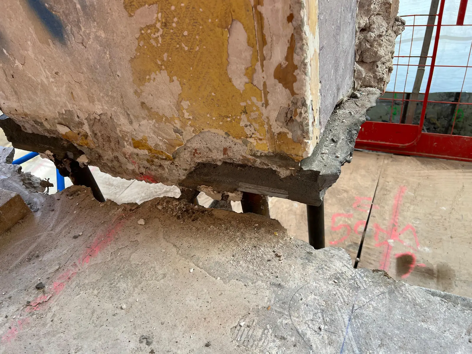 Mur porteur suspendu sur tabouret provisoire — le voile en attente est encore en charge, le plancher bas et le sol ont été retirés en dessous.